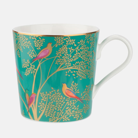 A fine china mug with a green background featuring colorful birds and gold detailing, handle on the right side.