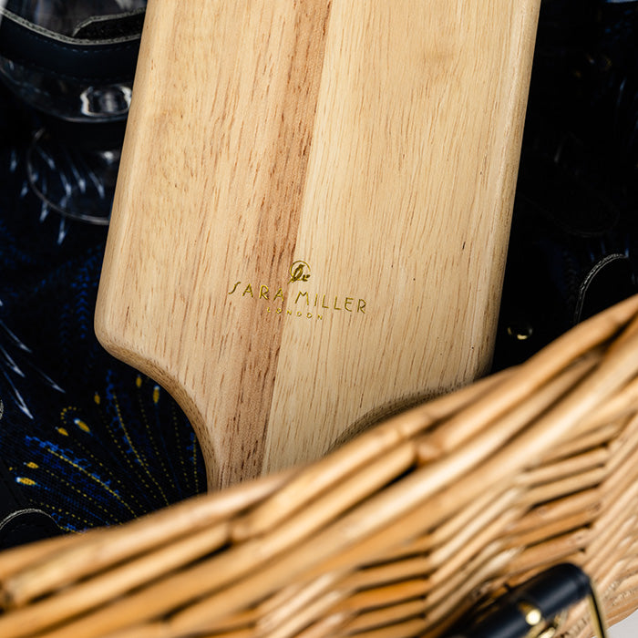 Wooden chopping board with 'Sara Miller London' branding on a dark background