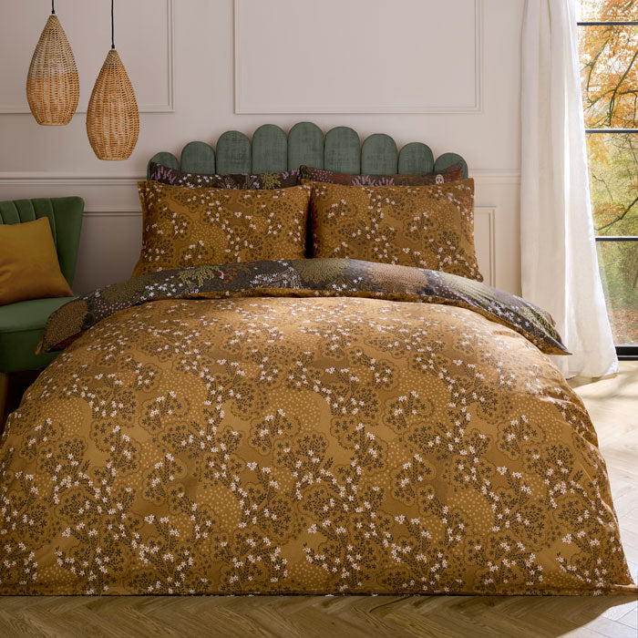 Bed with floral patterned bedding in a room with a window and decorative pillows.