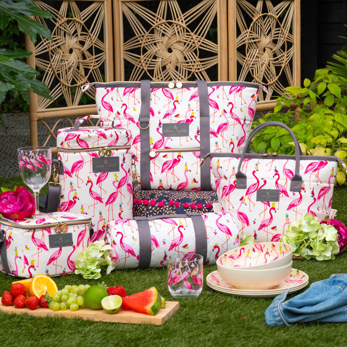 Flamingo-patterned picnic set with fruit and glasses on grass