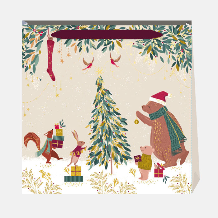 Gift bag with Christmas design featuring animals around a tree and presents.