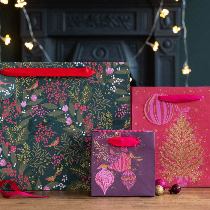 A collection of different sized gift bags all with festive foliage and Christmas tree patterns.