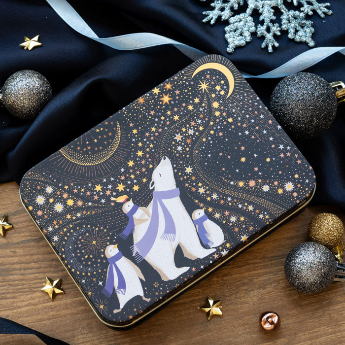 A rectangular metal tin with rounded corners, decorated with a winter night scene featuring a polar bear, penguins, stars, and moons on a dark navy background.