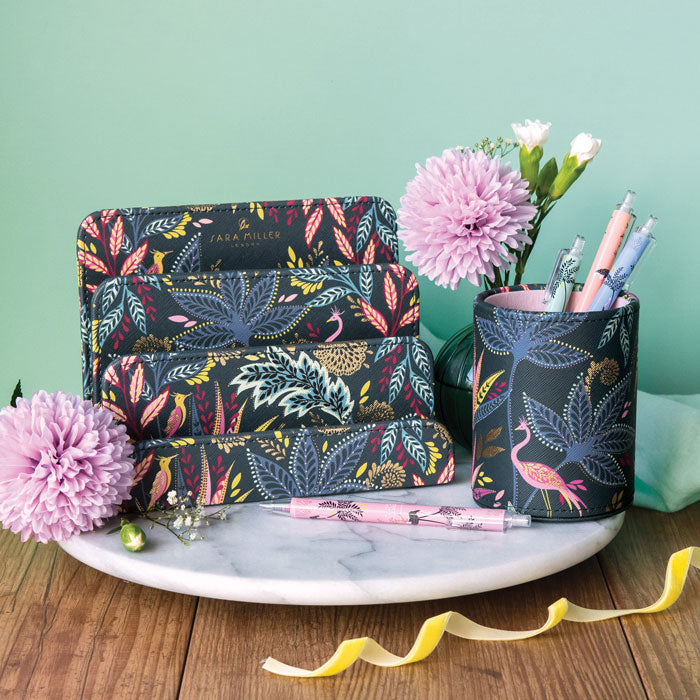 Floral-patterned letter holder and pen holder on a marble surface with flowers and ribbons.