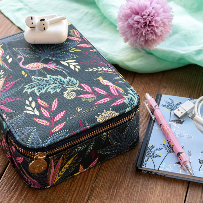 Patterned tech organiser with a notebook and pen on a wooden surface