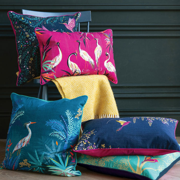 Five cushions stacked on a chair in blues, pink and green.