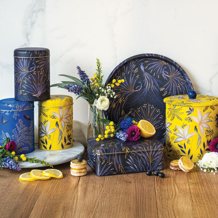 Tin storage containers in different shapes and colours, indigo, yellow and cobalt each in different floral and bird designs.