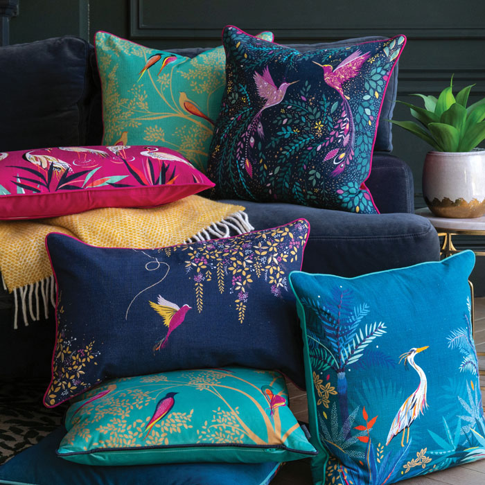 Collection of cushions stacked on the sofa in blues, green and pink.