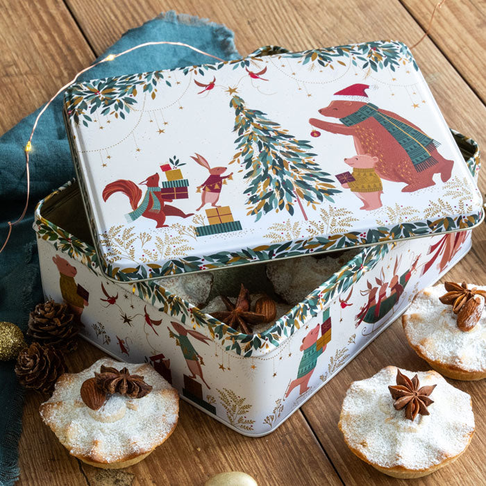 Decorative Christmas tin with festive illustrations on a wooden surface with mince pies.