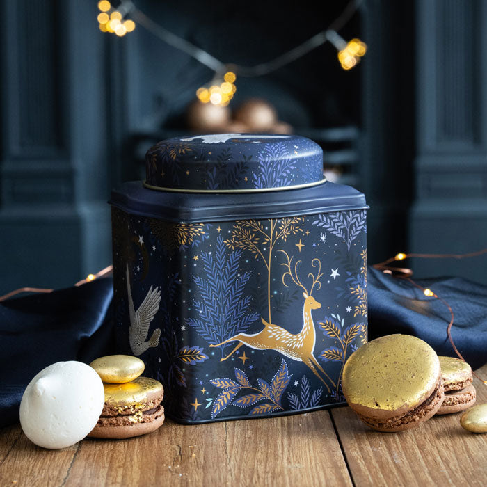Decorative caddy with gold reindeer design on a wooden surface with macarons.