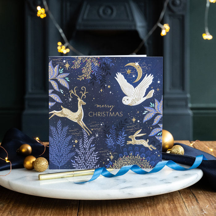 Decorative Christmas card with reindeer, dove, and foliage on a marble surface with festive decorations.