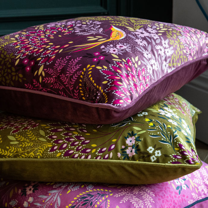 three cushions from the same collection all stacked, in shades of purple and green.