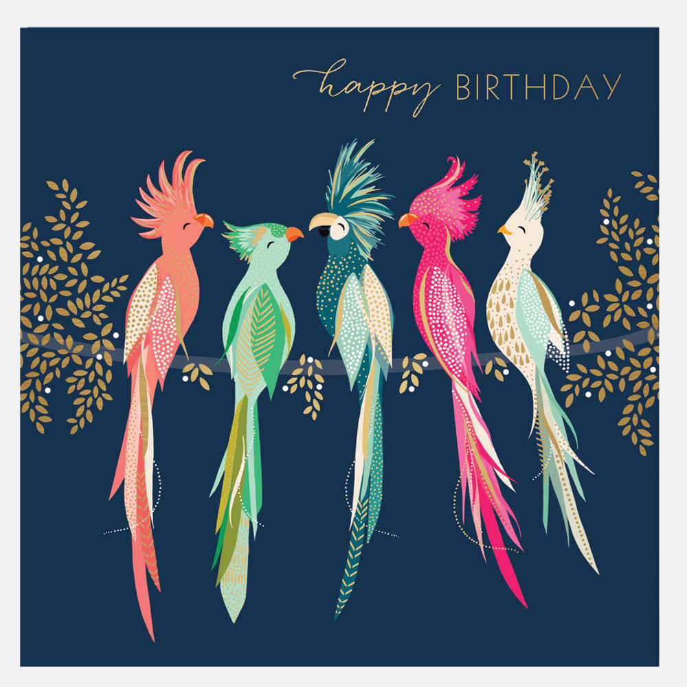 A colorful birthday card featuring illustrations of four tropical birds with a 'Happy Birthday' greeting, surrounded by tropical foliage, in a gold foil finish.