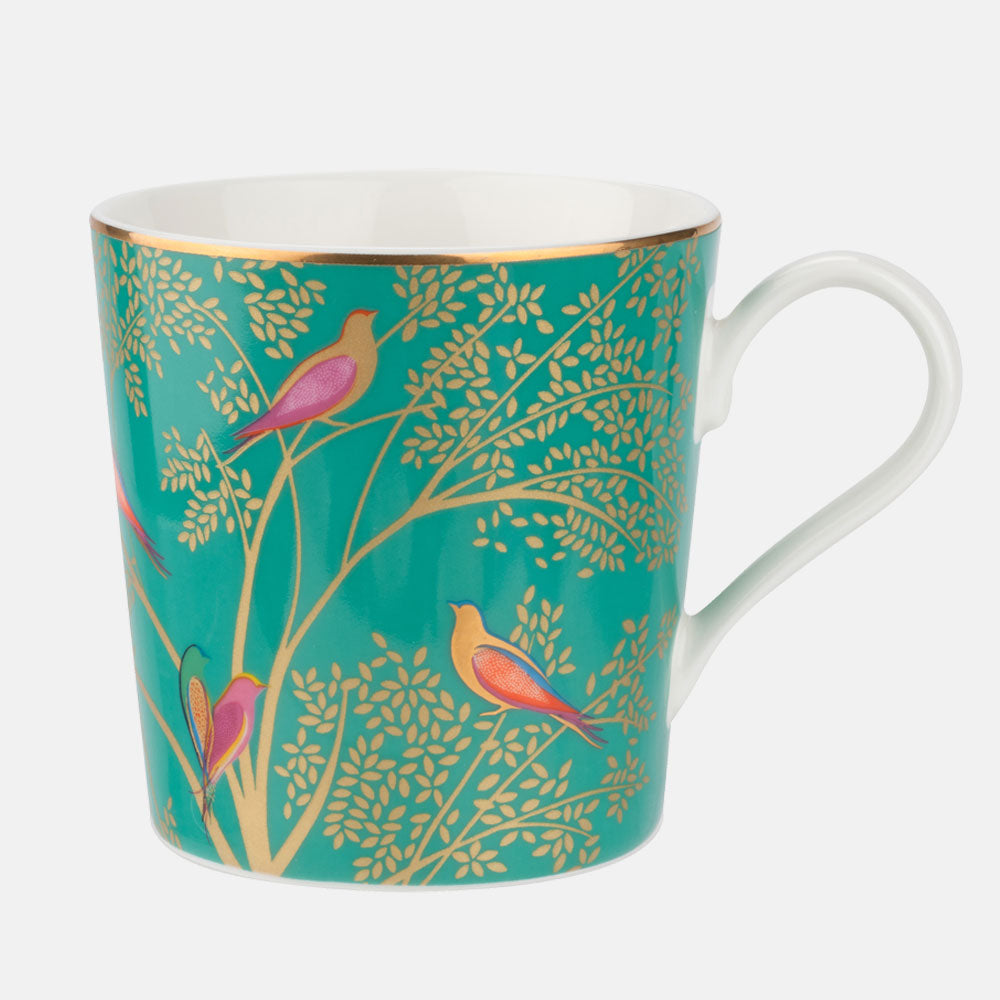 A fine china mug with a green background featuring colorful birds and gold detailing, handle on the right side.