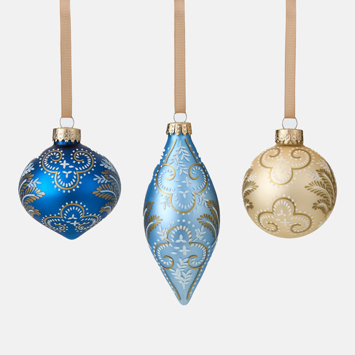 Three decorative Christmas ornaments in blue, light blue, and gold on a white background