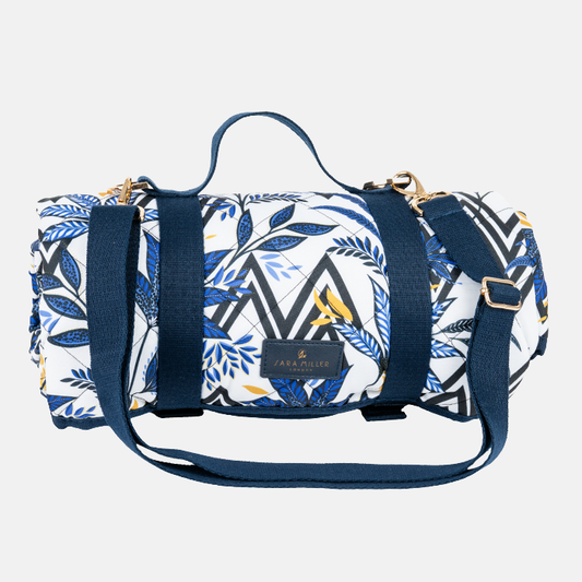 Picnic blanket rolled up with blue and white pattern with carry handles/straps