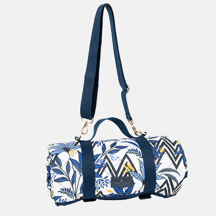 Picnic blanket rolled up with blue and white pattern with carry handles/straps