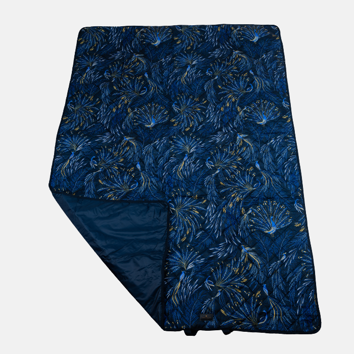 Indigo peacock patterned picnic blanket on a light grey background
