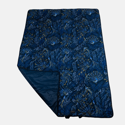 Indigo peacock patterned picnic blanket on a light grey background