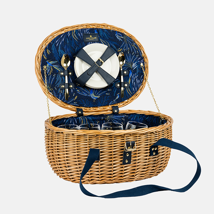 Open picnic basket with blue interior, cutlery, and glasses on a white background