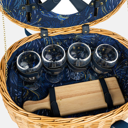 Open picnic basket with wicker exterior and blue interior, containing wine glasses and a wooden cutting board.
