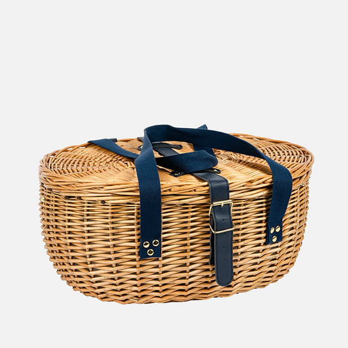 Wicker picnic basket with navy straps on a white background