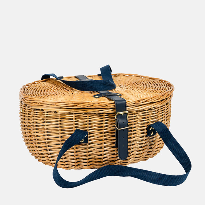 Wicker picnic basket with navy straps on a white background
