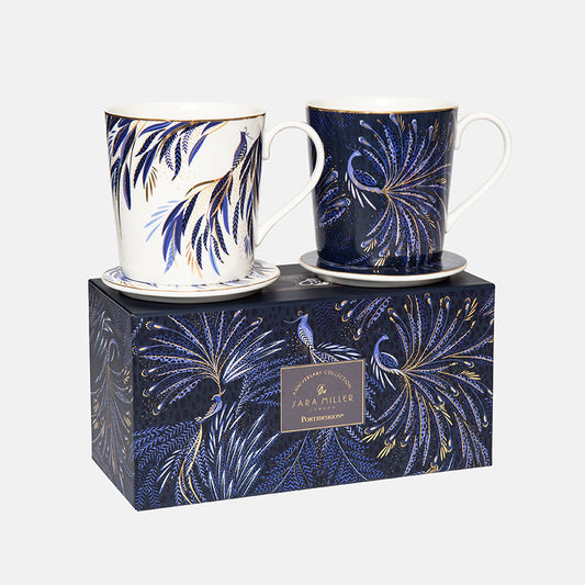 Two decorative mugs and coasters with peacock patterns on a matching box, with gold detailing.