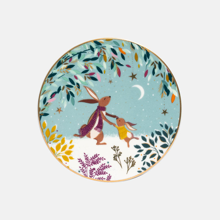 A round decorative coaster featuring an illustrated scene of two rabbits holding hands under a crescent moon, surrounded by autumn leaves and stars on a light green background.