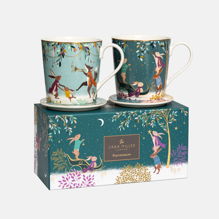 A boxed fine china mug set by Sara Miller London featuring two mugs with woodland characters on green backgrounds, displayed on top of the branded gold embellished gift box.