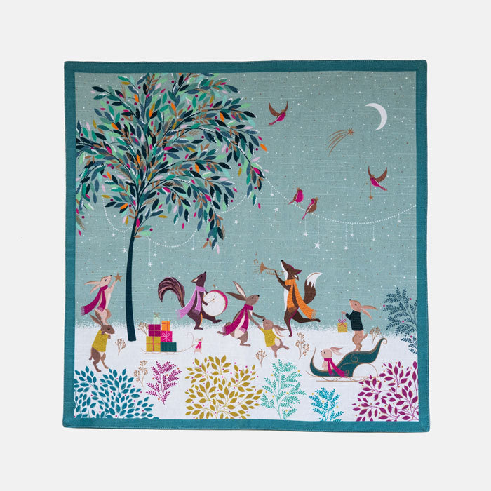 The napkin folded out so can see whole design, woodland animals in a merry band in a moonlit woodland scene green background.