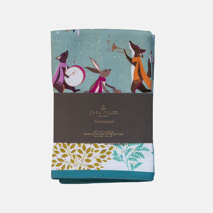 Fabric napkins by Sara Miller London with a whimsical illustration of woodland animals playing musical instruments against a green background, a grey paper band across the middle.