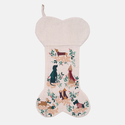 Bone shaped festive stocking with dogs dressed in scarves and jumpers and festive foliage on a cream background.