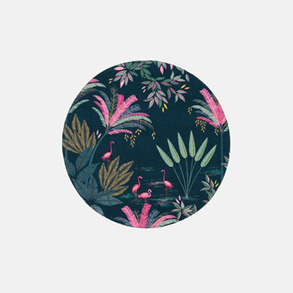 A round fabric placemat with flamingo and palms design on a dark green background.