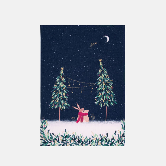 Festive tea towel with rabbits in moonlight design, and Christmas trees on a starry sky background.