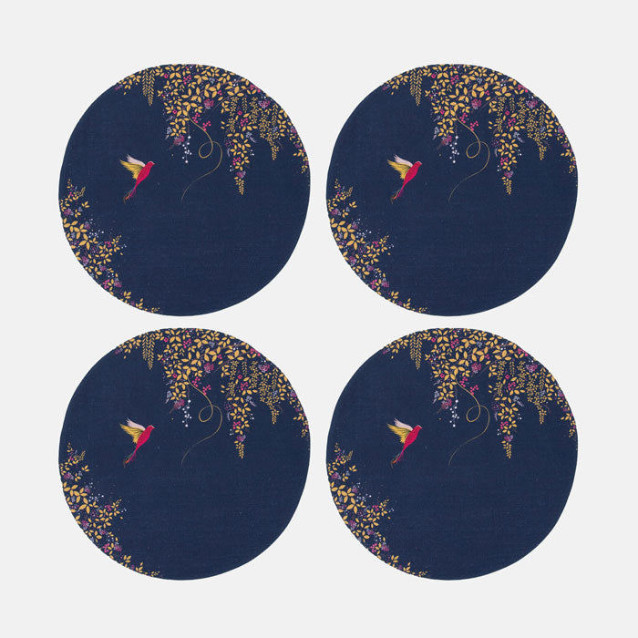 Set of four identical round placemats with floral and bird design on a dark blue background