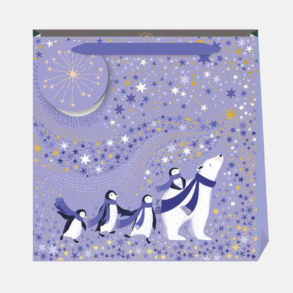 A periwinkle Christmas gift bag with penguins and a polar bear against a starry sky.
