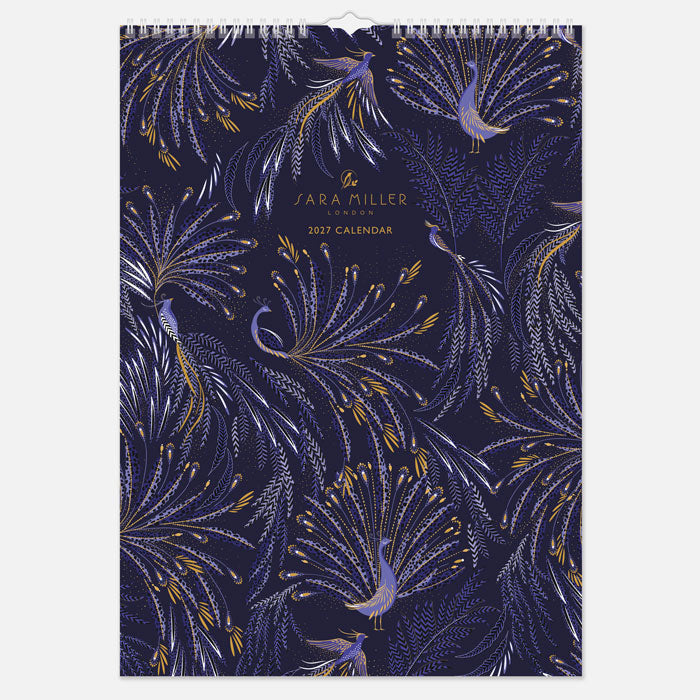 A hanging spiral bound wall calendar with intricate blue peacock design with gold detailing.