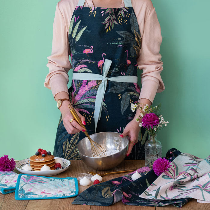 Apron with flamingo and palm design on a navy background.