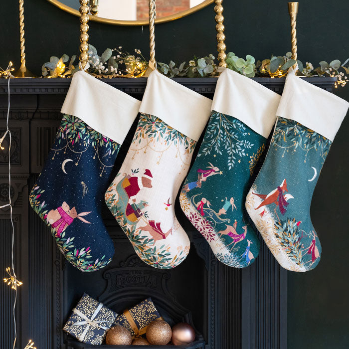 Four decorative Christmas stockings hanging above a fireplace with festive decorations.