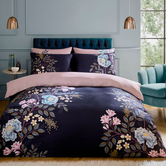 Navy floral bedding set on a bed in a stylish bedroom with a teal chair and window.