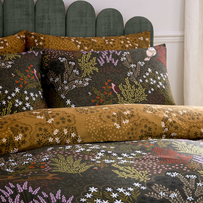 Floral patterned bedding set on a bed with a green headboard.