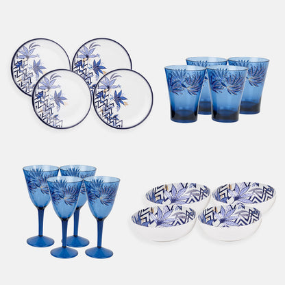 Set of four plastic plates, bowls, tumblers and wine glasses against a plain background.