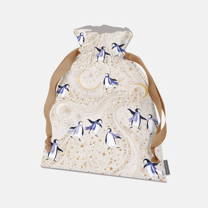 A drawstring present bag featuring a whimsical penguin and moon pattern on a cream background, with tan drawstrings.