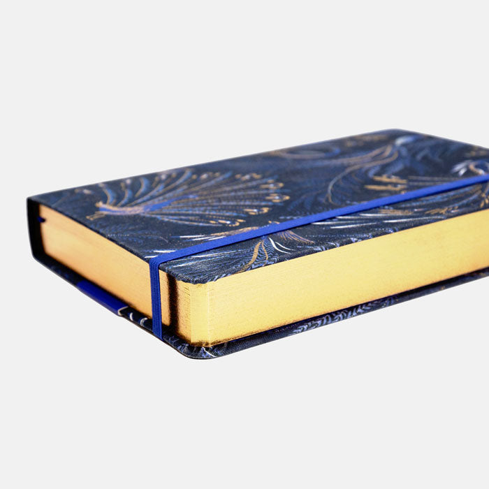 Notebook with peacock feather design on an indigo background with gold detailing, gold edged pages.