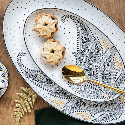 A stack of medium and large serving platters with black and white delicate patetrns.