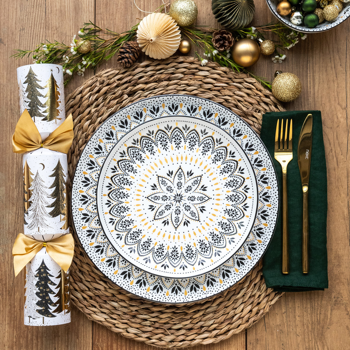 A black and white mandala patterned side and dinner plate stacked in a festive place setting.