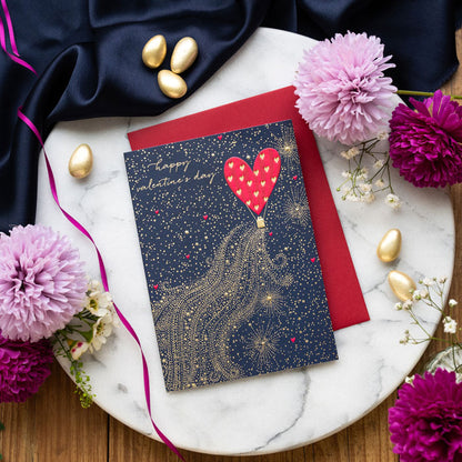 Valentine's Day card with heart design on a marble surface with flowers and ribbons.