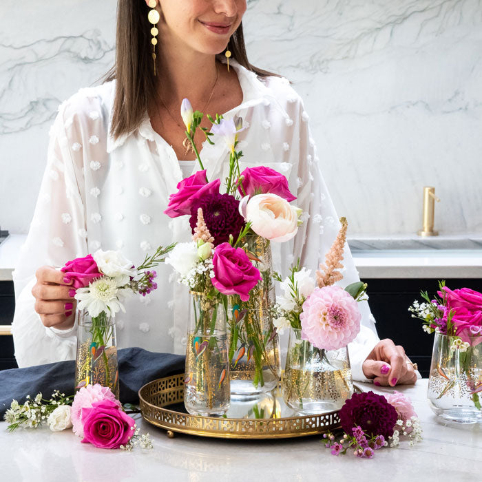 A collection of different sized gold embellished vases with bird design on a kitchen counter, styled with flowers.