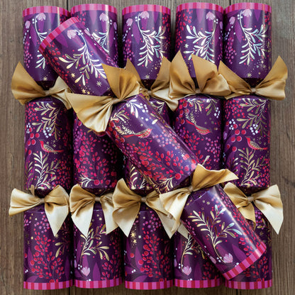 A set of six plum Christmas crackers with winter foliage, berries and robins finished with gold ribbons. 